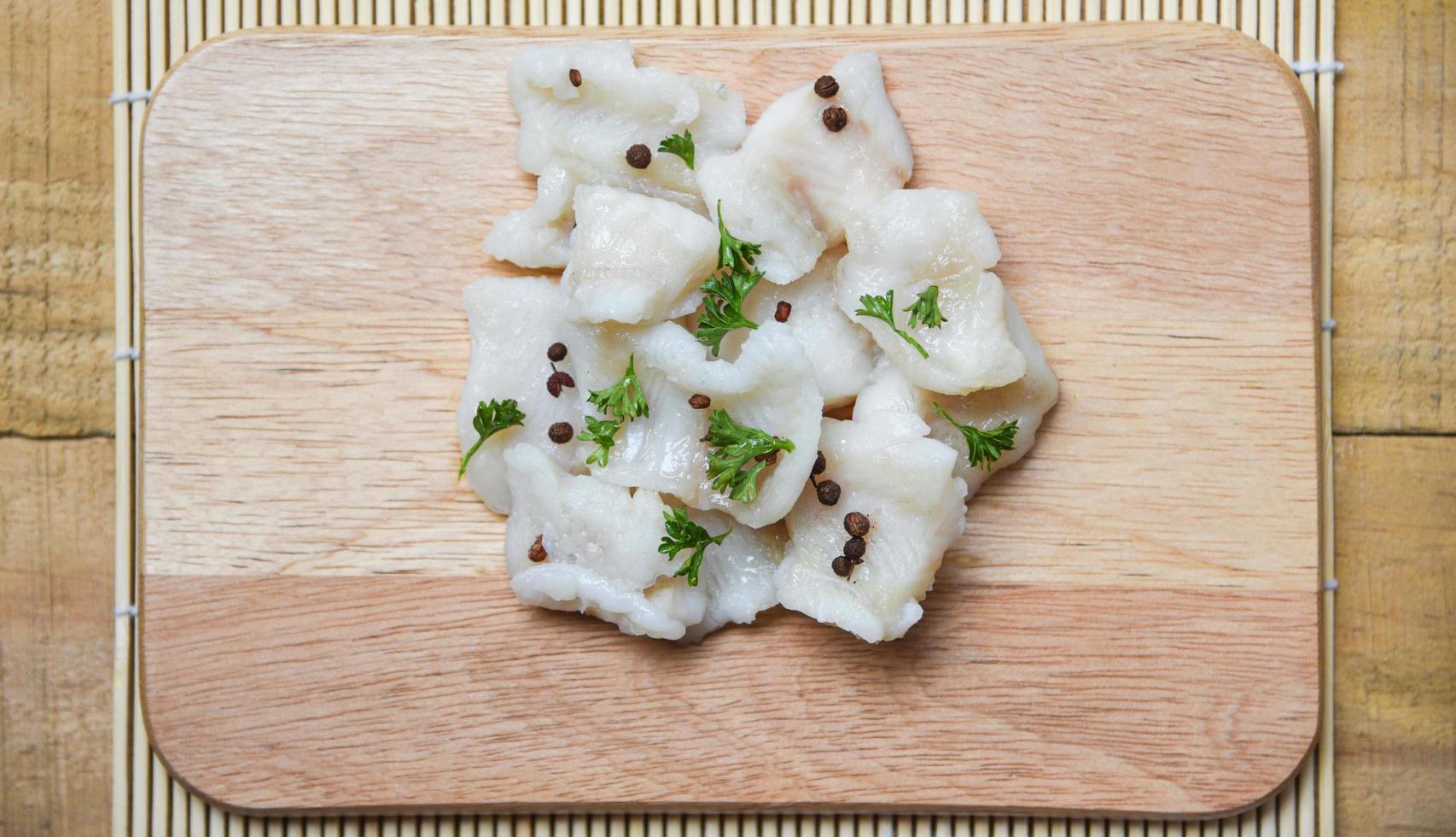 pezzo di filetto di pesce cotto con spezie su sfondo di tagliere di legno - carne di pesce pangasio dolly foto