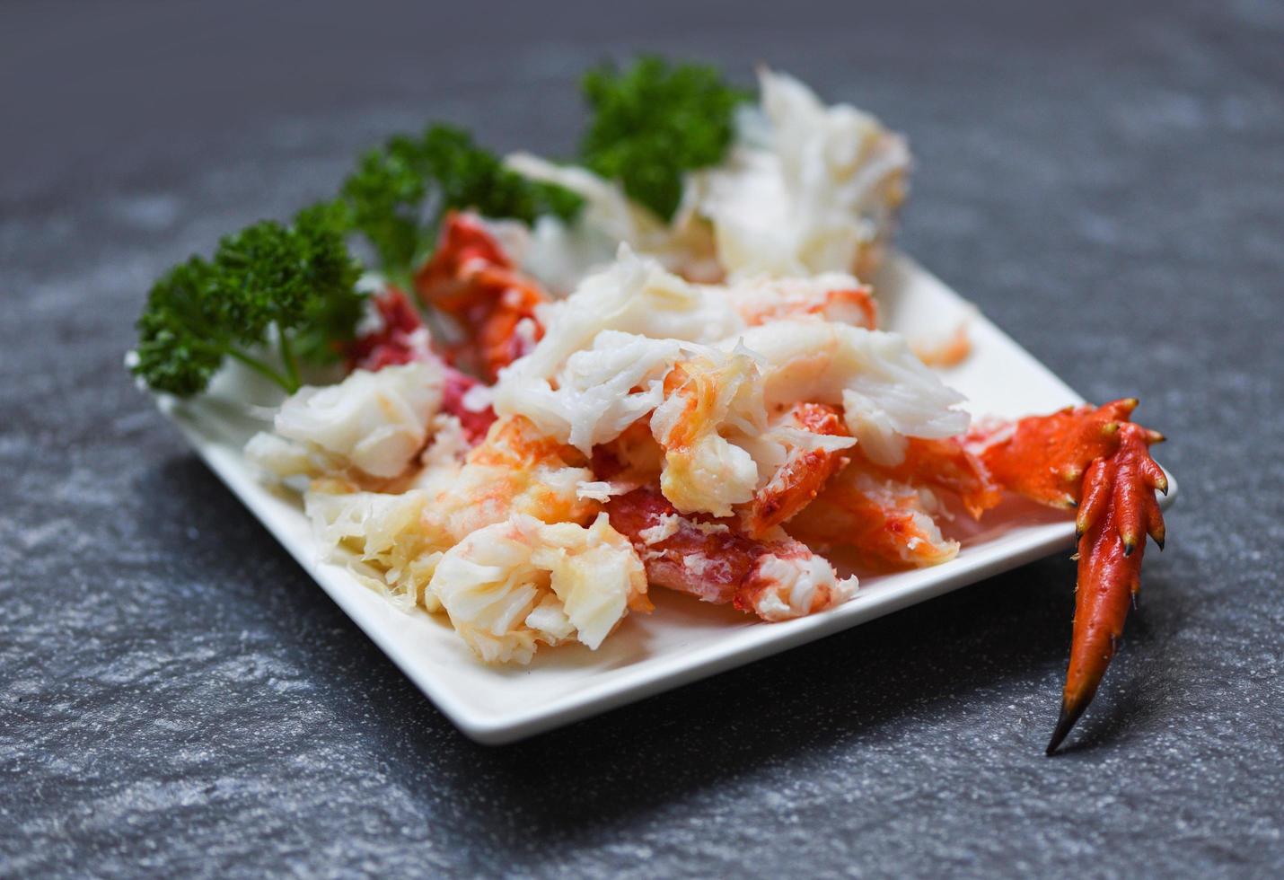 polpa di granchio su piatto bianco con spezie per frutti di mare cotti - gambe di granchio rosso foto