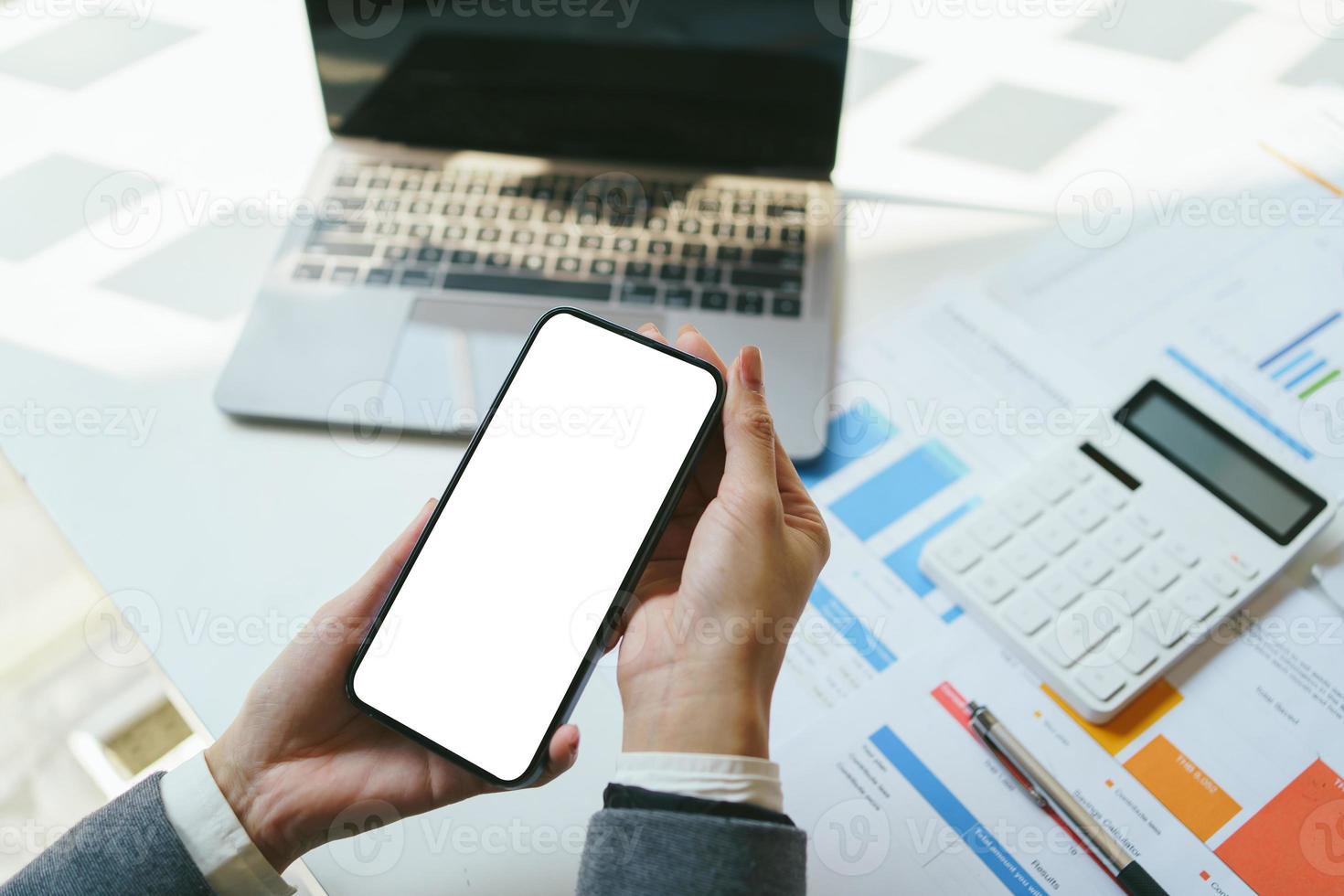 immagine mockup di mani che tengono e utilizzano un telefono cellulare nero con schermo desktop vuoto in ufficio. tracciato di ritaglio. foto