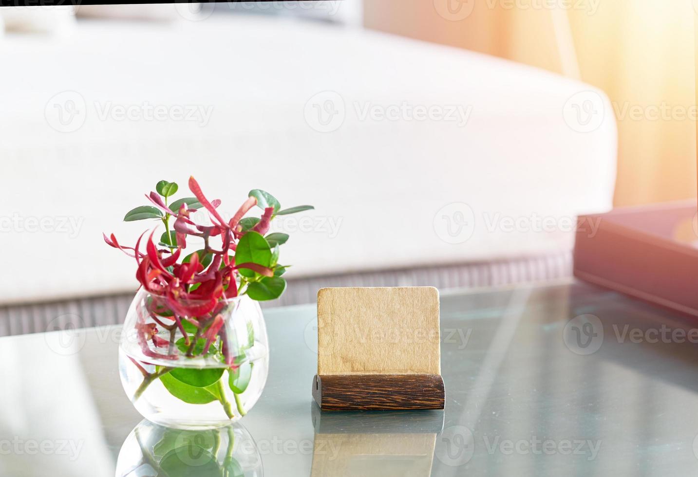 mock up supporto per etichette con vaso d'acqua floreale sul tavolo in camera per il concetto di accoglienza di benvenuto foto