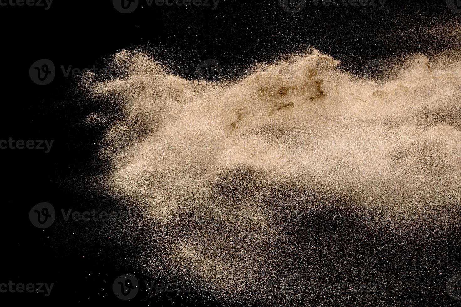 esplosione di sabbia di fiume secca. spruzzata di sabbia color oro su sfondo scuro. foto