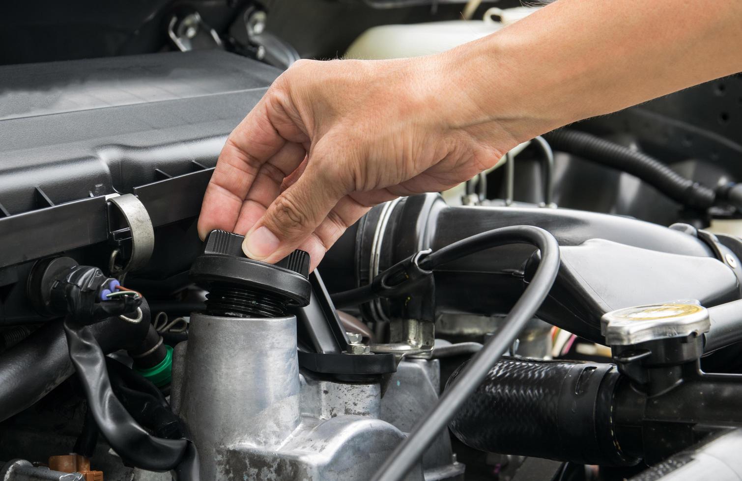 un meccanico sta aprendo il tappo dell'olio da un motore di un'auto. foto