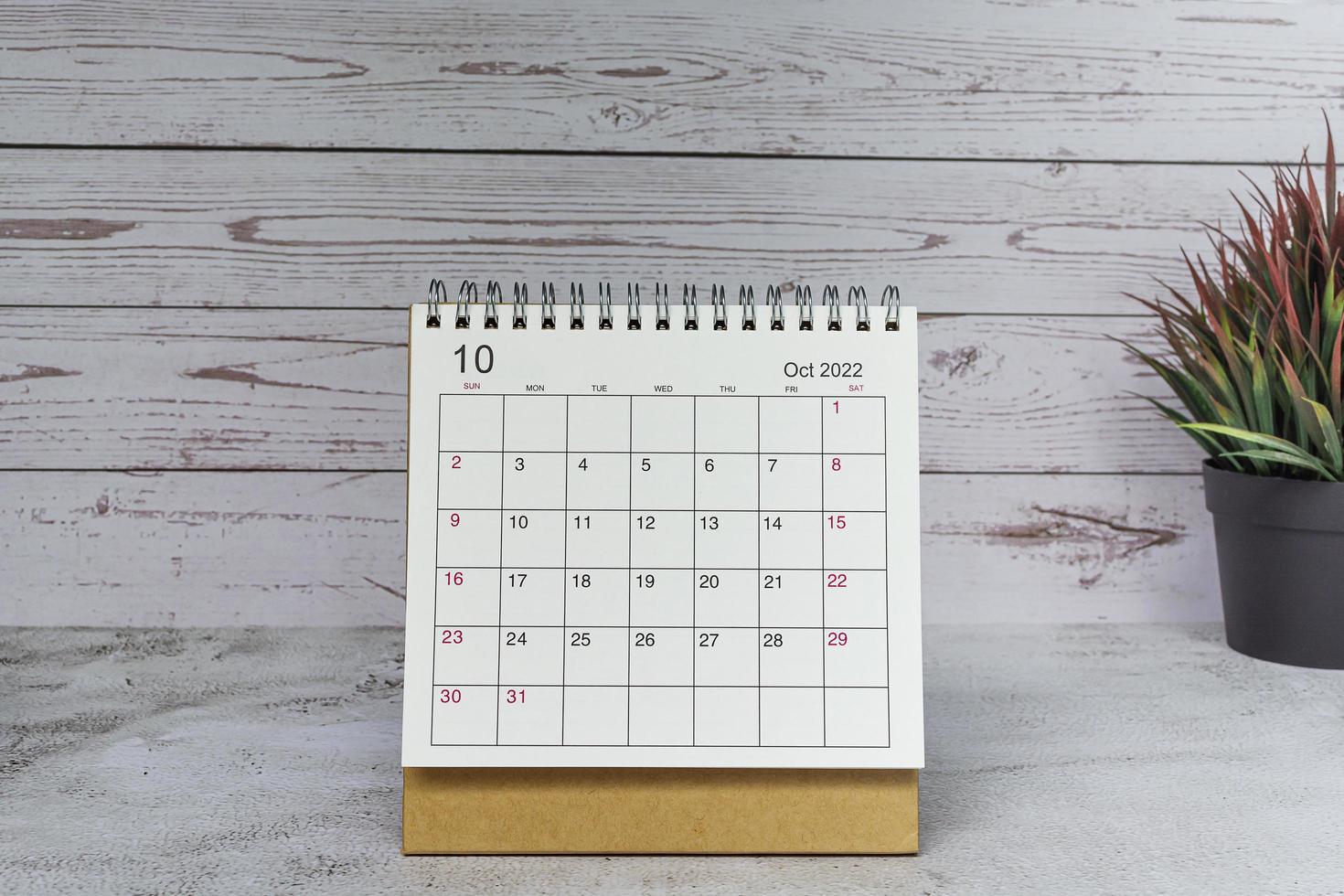calendario bianco ottobre 2022 con pianta in vaso su scrivania in legno. 2022 concetto di nuovo anno foto