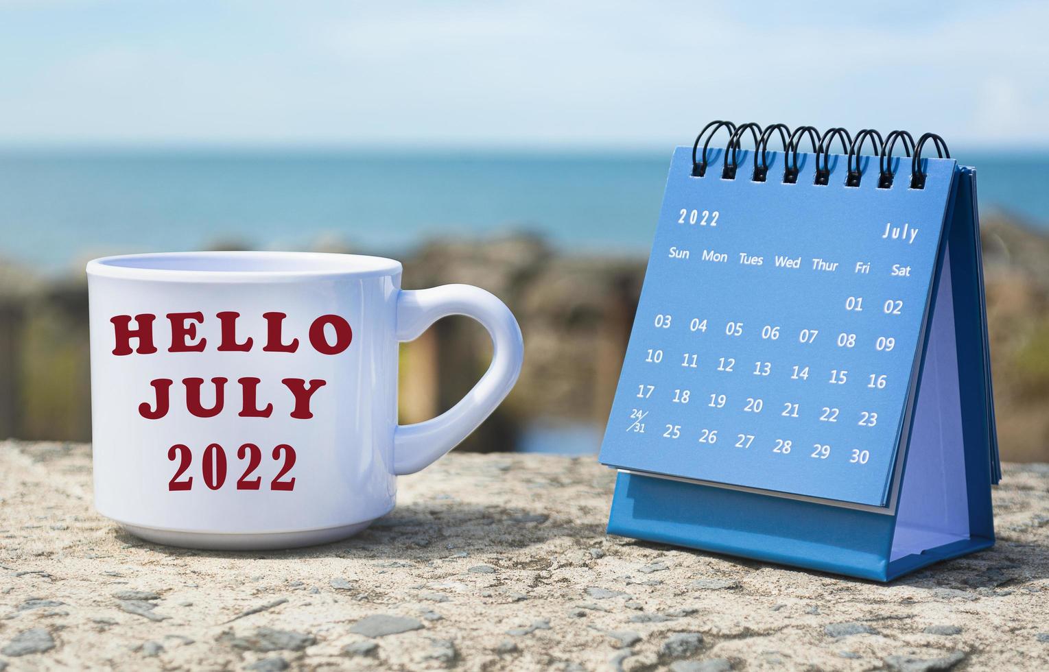 ciao luglio 2022 scritto su tazza da caffè bianca con calendario blu foto