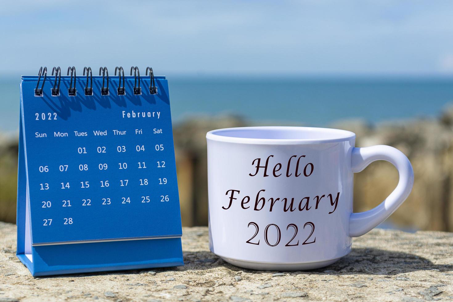 ciao febbraio 2022 scritto su una tazza di caffè bianca con calendario blu foto