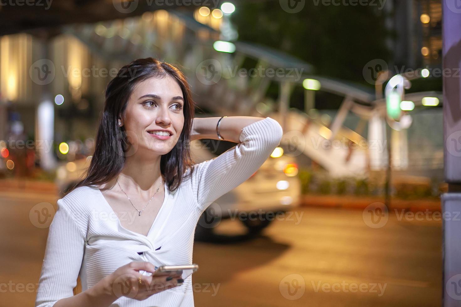 bella donna uso del telefono cellulare in una strada di città di notte foto