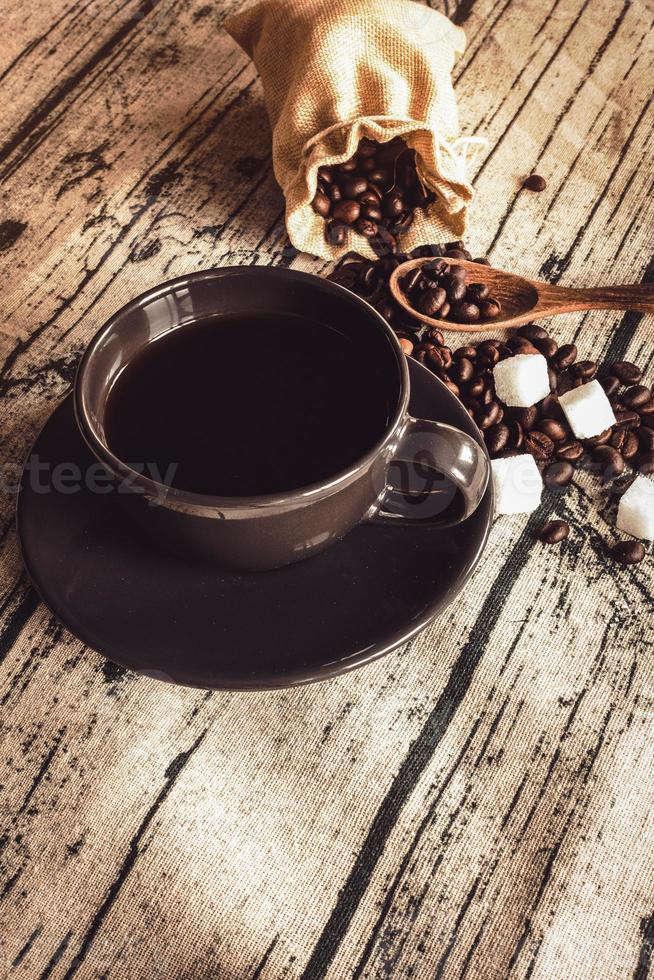 tazza di caffè con i fagioli su un tessuto di lino da tavola in legno. foto