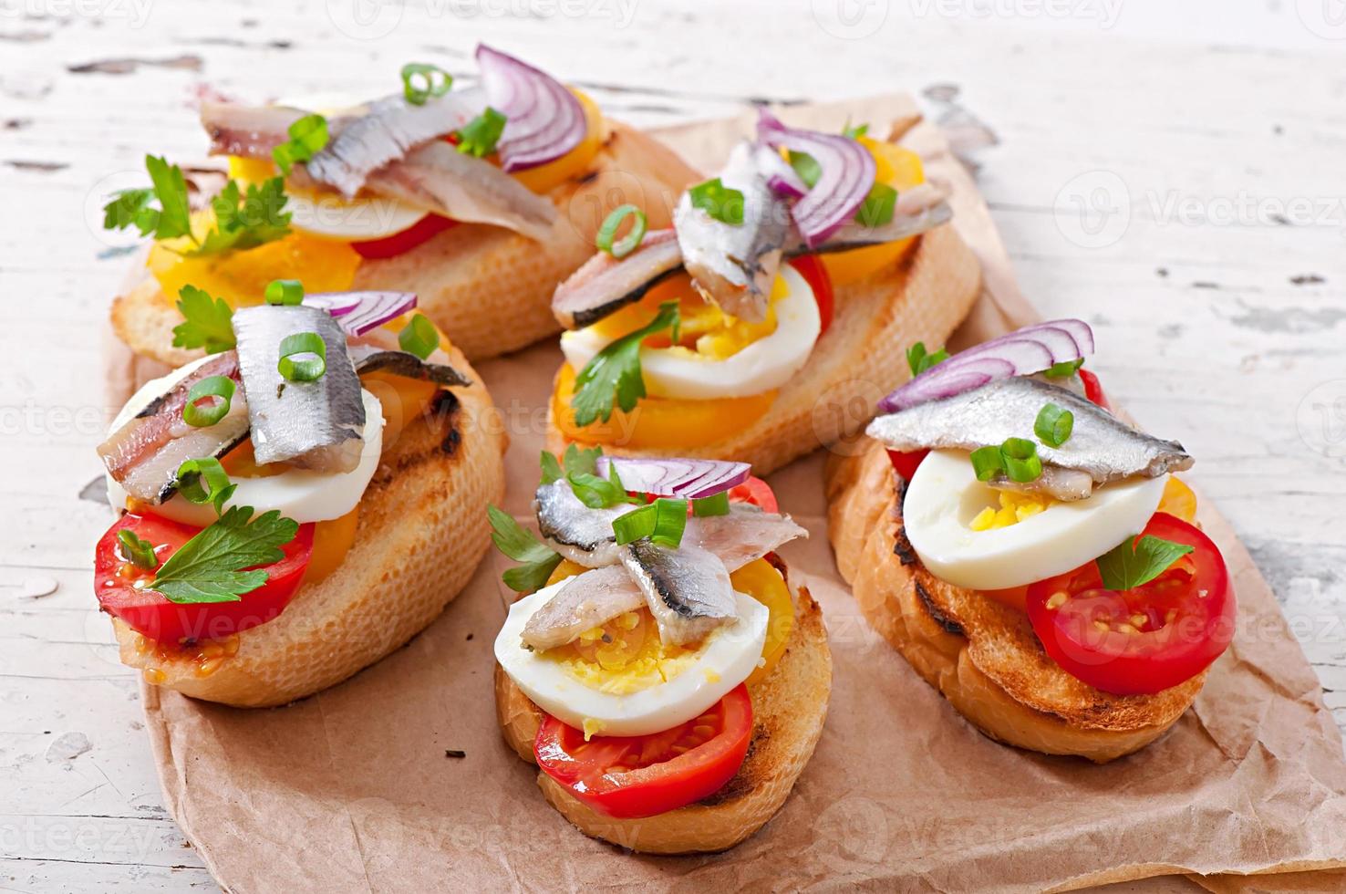 crostini con acciughe, pomodori e uovo, decorati con verdure foto