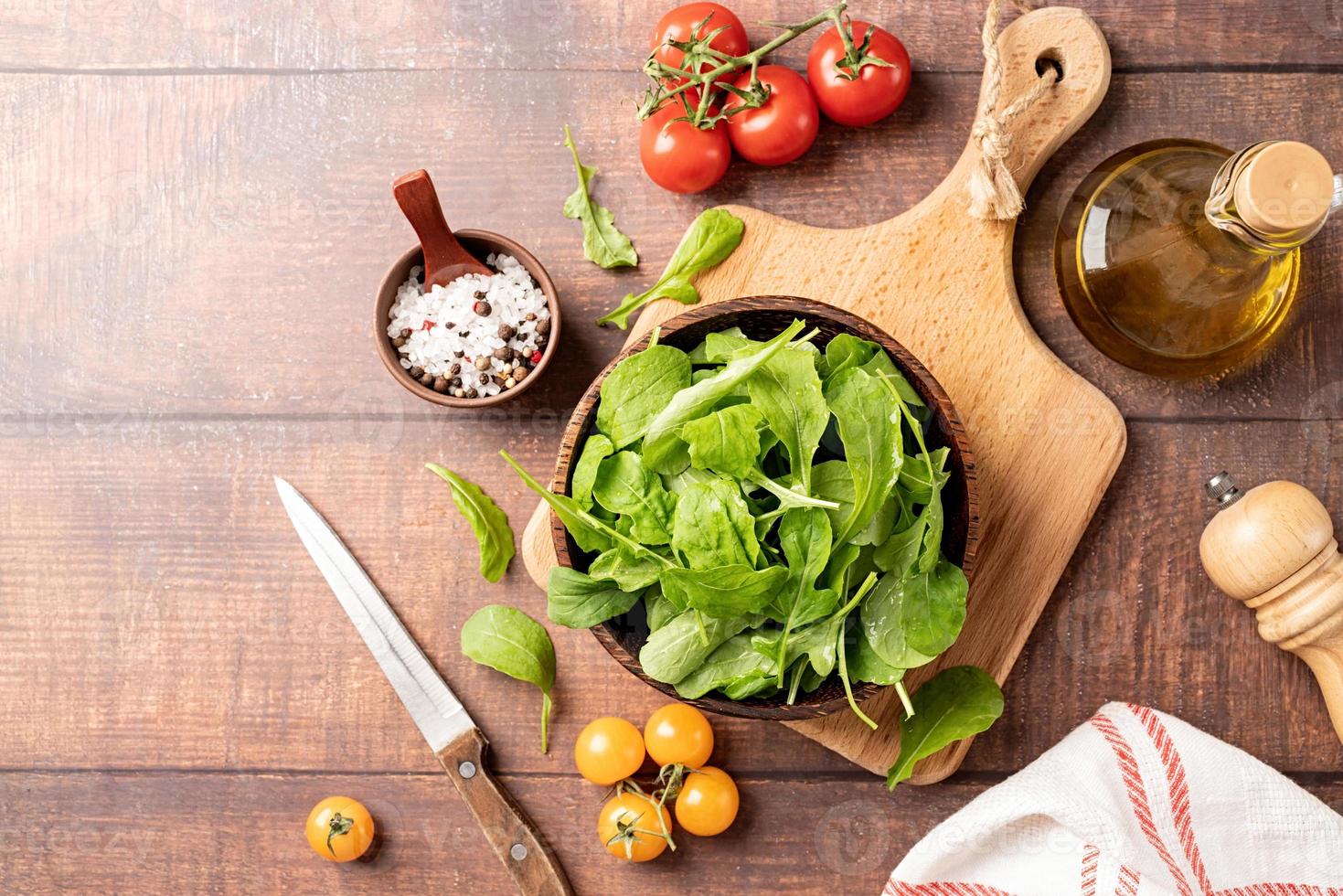 foglie di rucola fresca in una ciotola marrone con verdure fresche foto