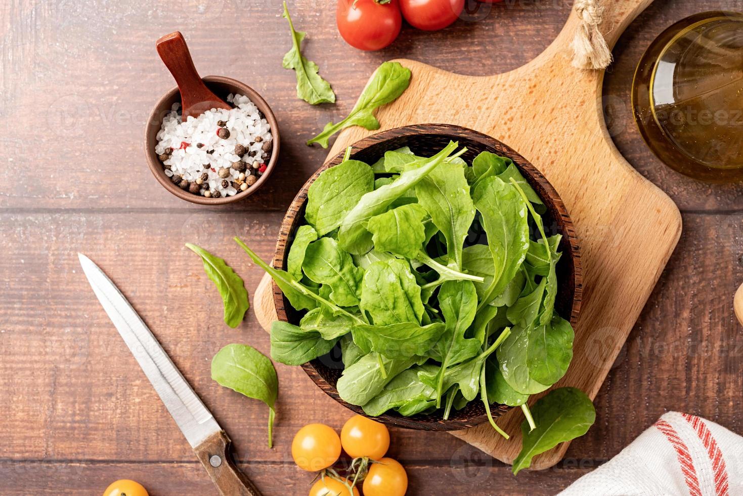 foglie di rucola fresca in una ciotola marrone con verdure fresche foto