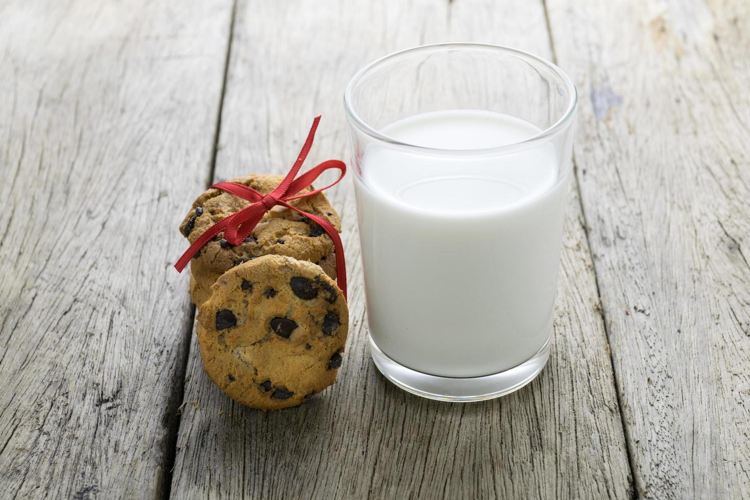 biscotti e un bicchiere di latte sul tavolo di legno foto