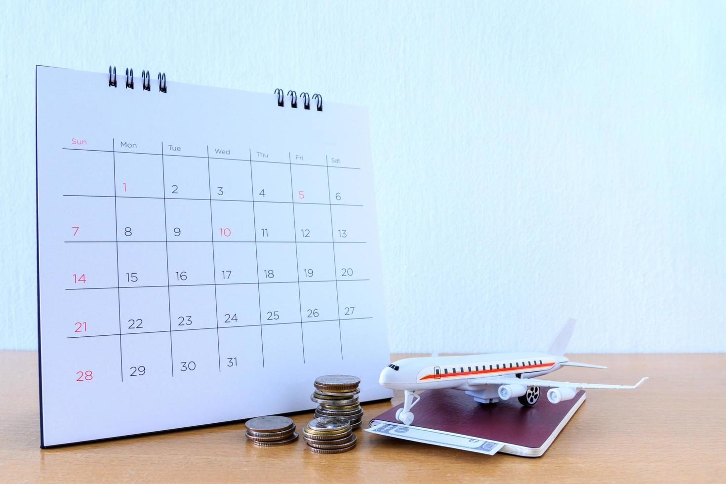 modello di aeroplano con calendario di carta sul tavolo di legno. pianificare il viaggio foto