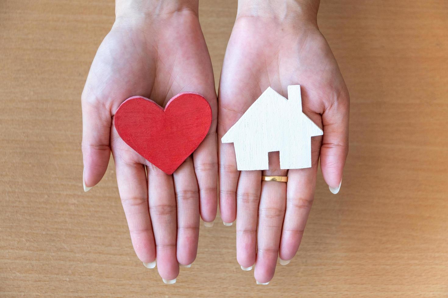 mani della donna che tengono cuore rosso e casa dell'icona foto