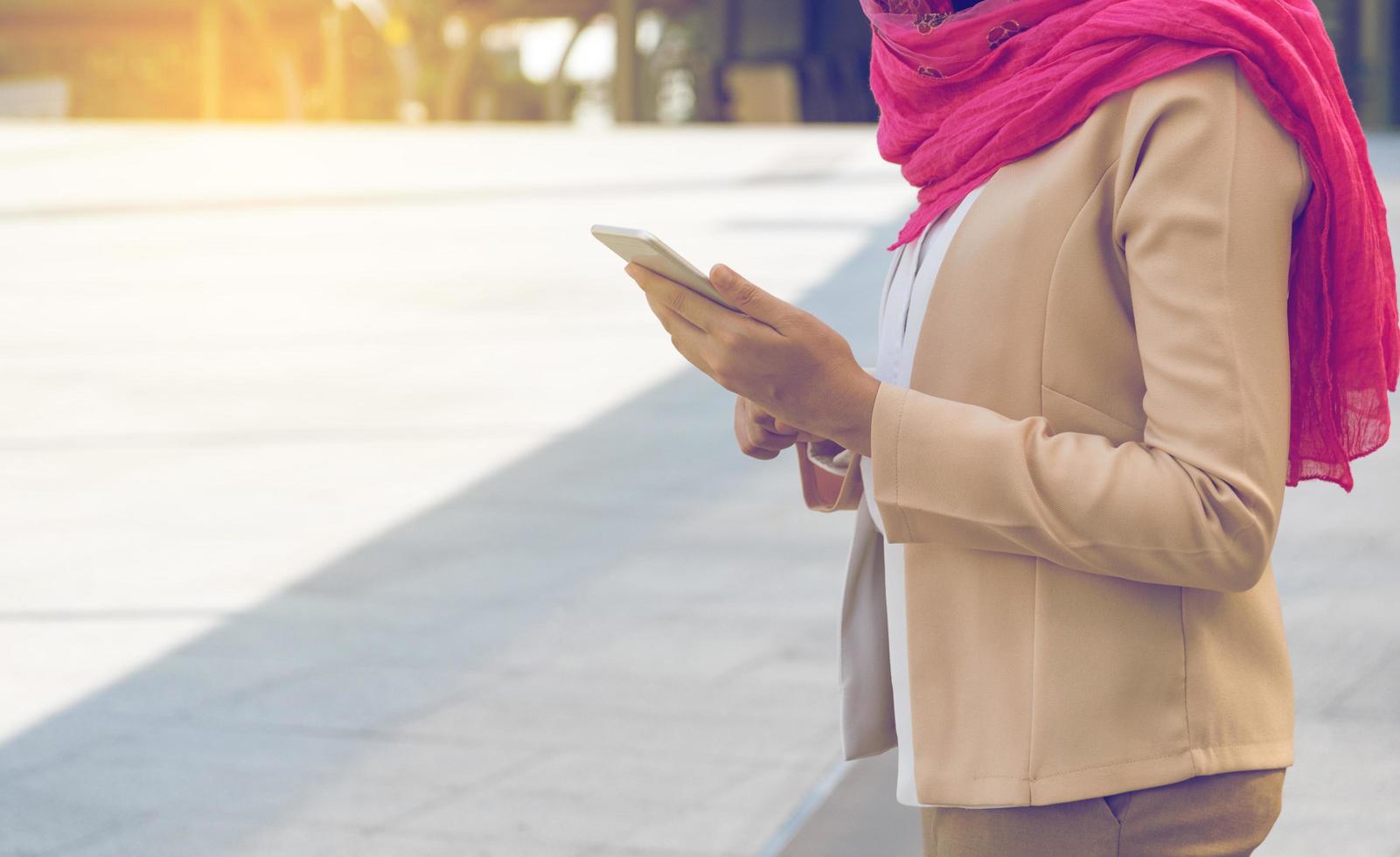 donna musulmana che messaggia su un telefono cellulare in città foto