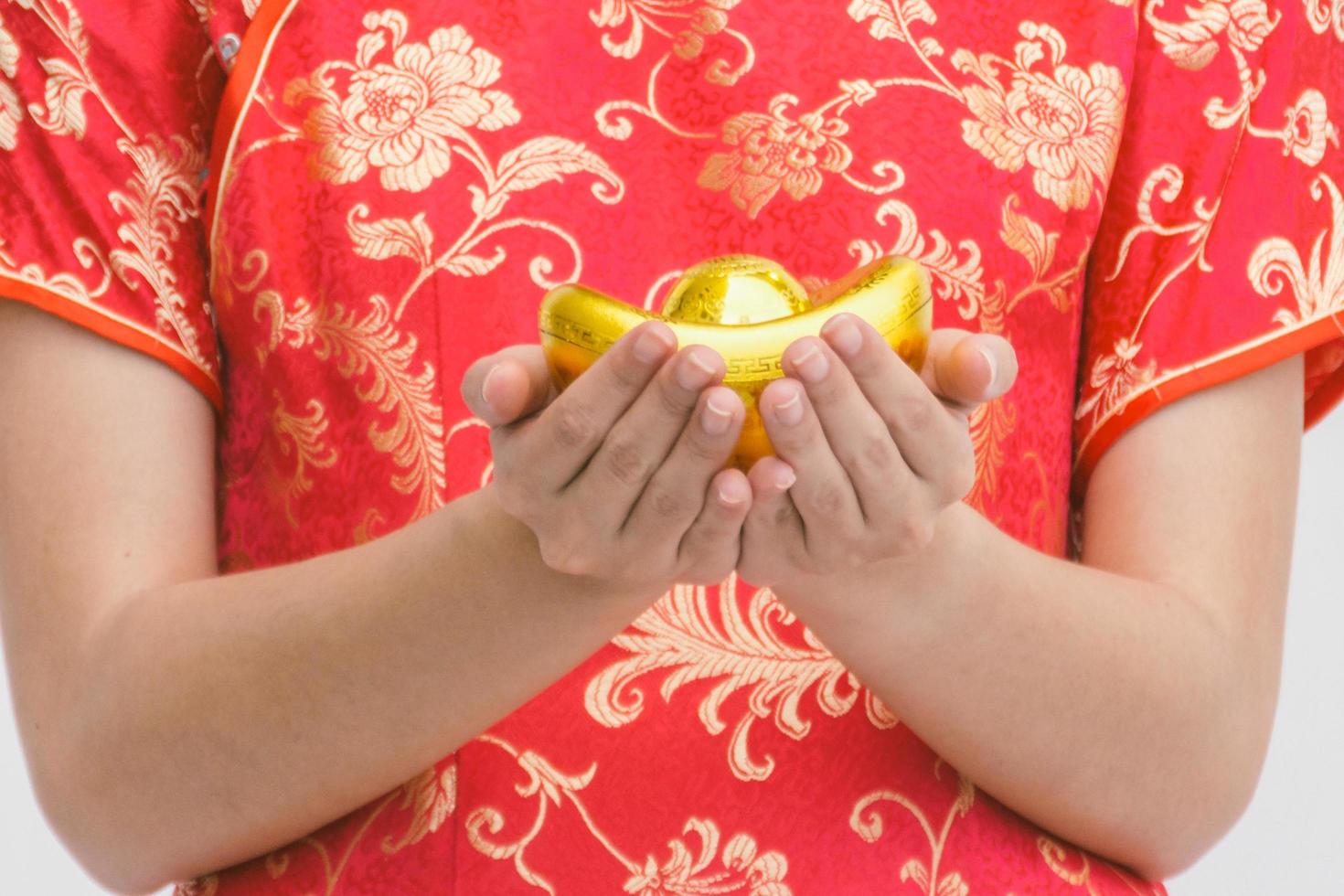 donna asiatica con cheongsam che tiene oro. Capodanno cinese. foto