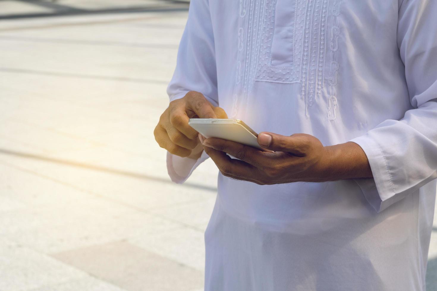 uomo d'affari arabo messaggistica su un telefono cellulare in città foto