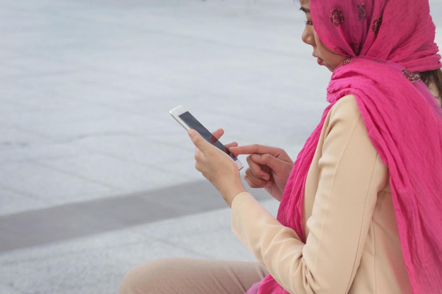 messaggistica araba della donna di affari su un telefono cellulare nella città foto