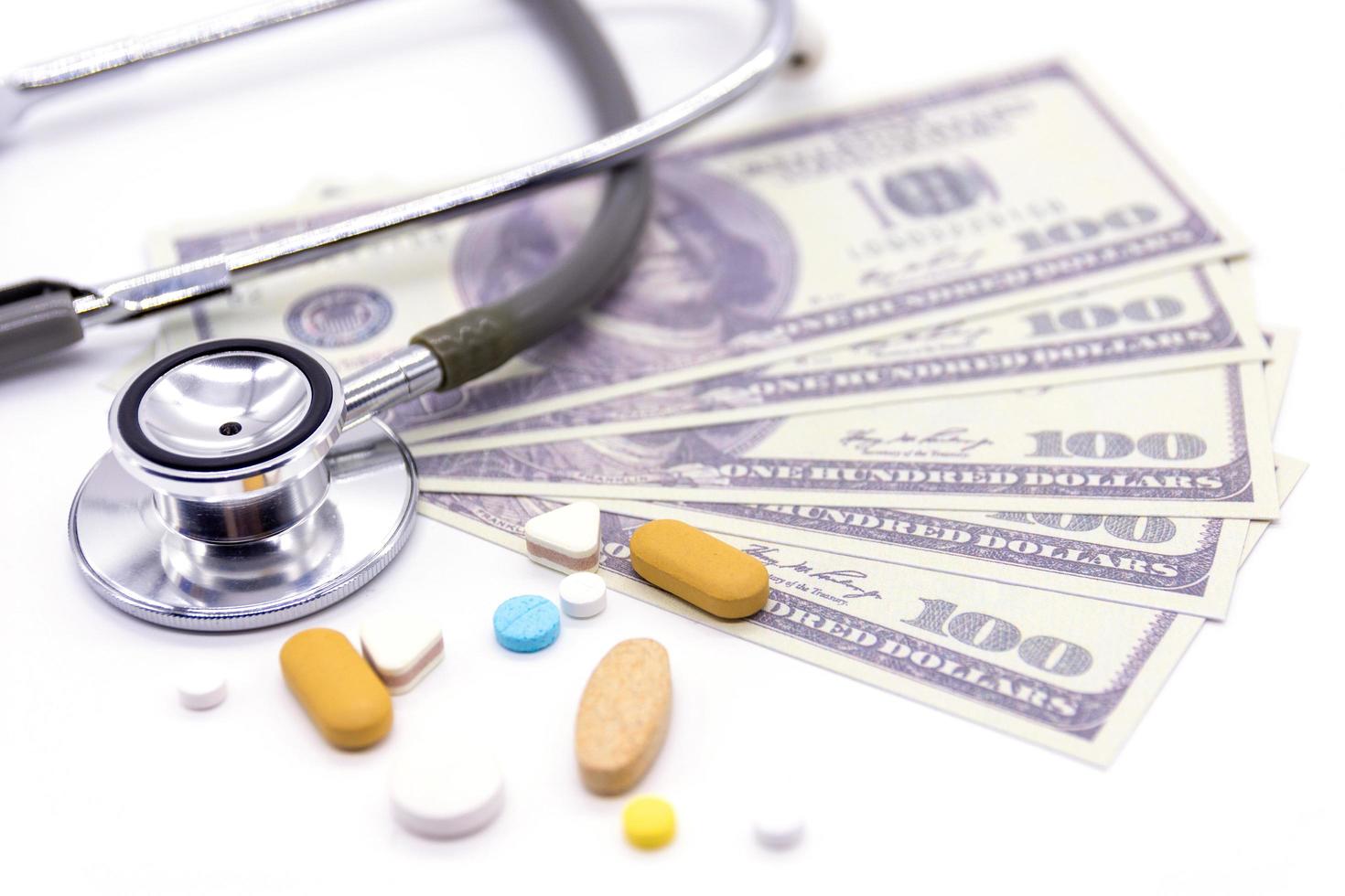 stetoscopio con banca del dollaro e capsule medicinali su sfondo bianco. stile di vita sano con il concetto di finanza aziendale foto