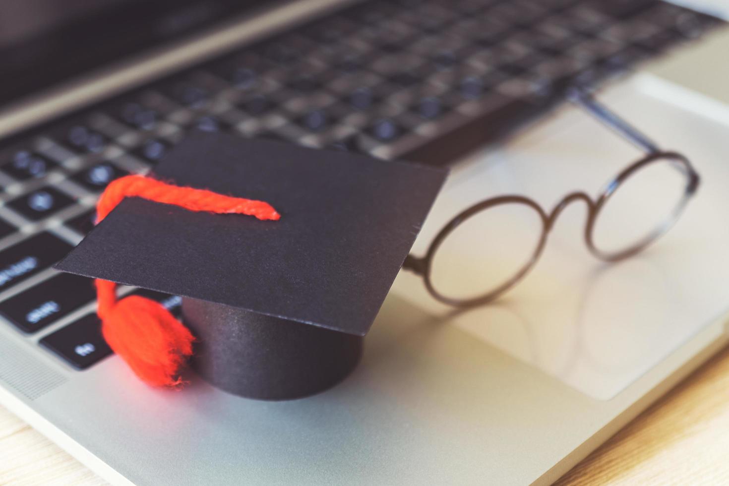 modello di cappello di laurea e taccuino sulla scrivania in legno. foto