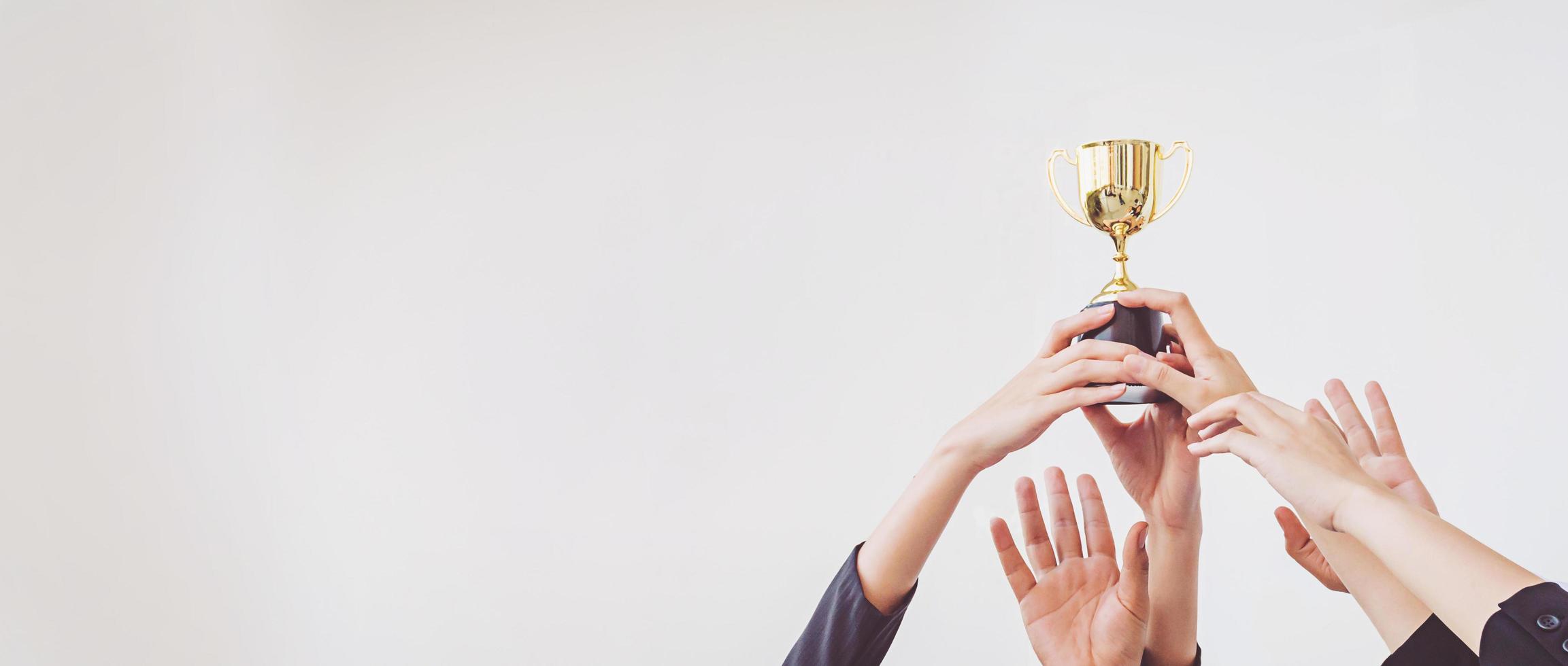 le mani si arrampicano per la coppa del trofeo d'oro, concetto di business foto