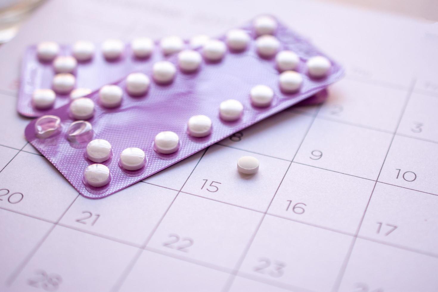 pillola anticoncezionale con data di sfondo del calendario, assistenza sanitaria e concetto di medicina foto