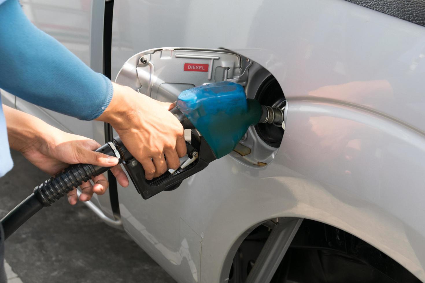 gli uomini tengono l'ugello del carburante per aggiungere carburante in auto alla stazione di servizio foto