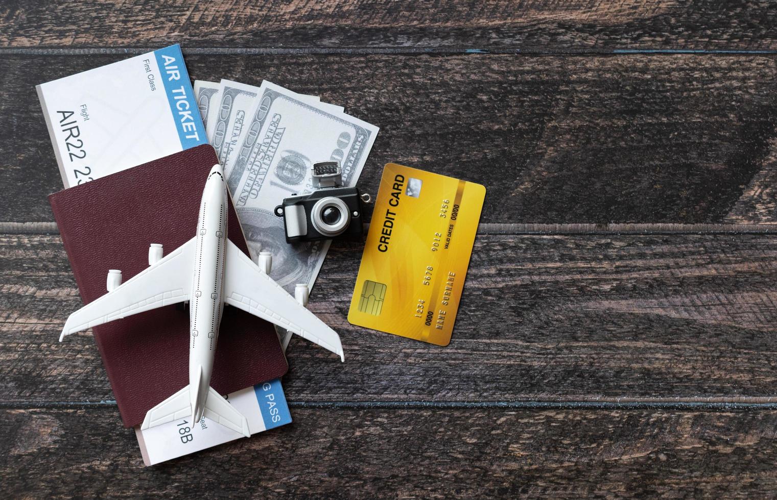 aeroplano giocattolo, biglietto aereo, carte di credito, dollari e passaporto su tavola di legno. concetto di viaggio foto