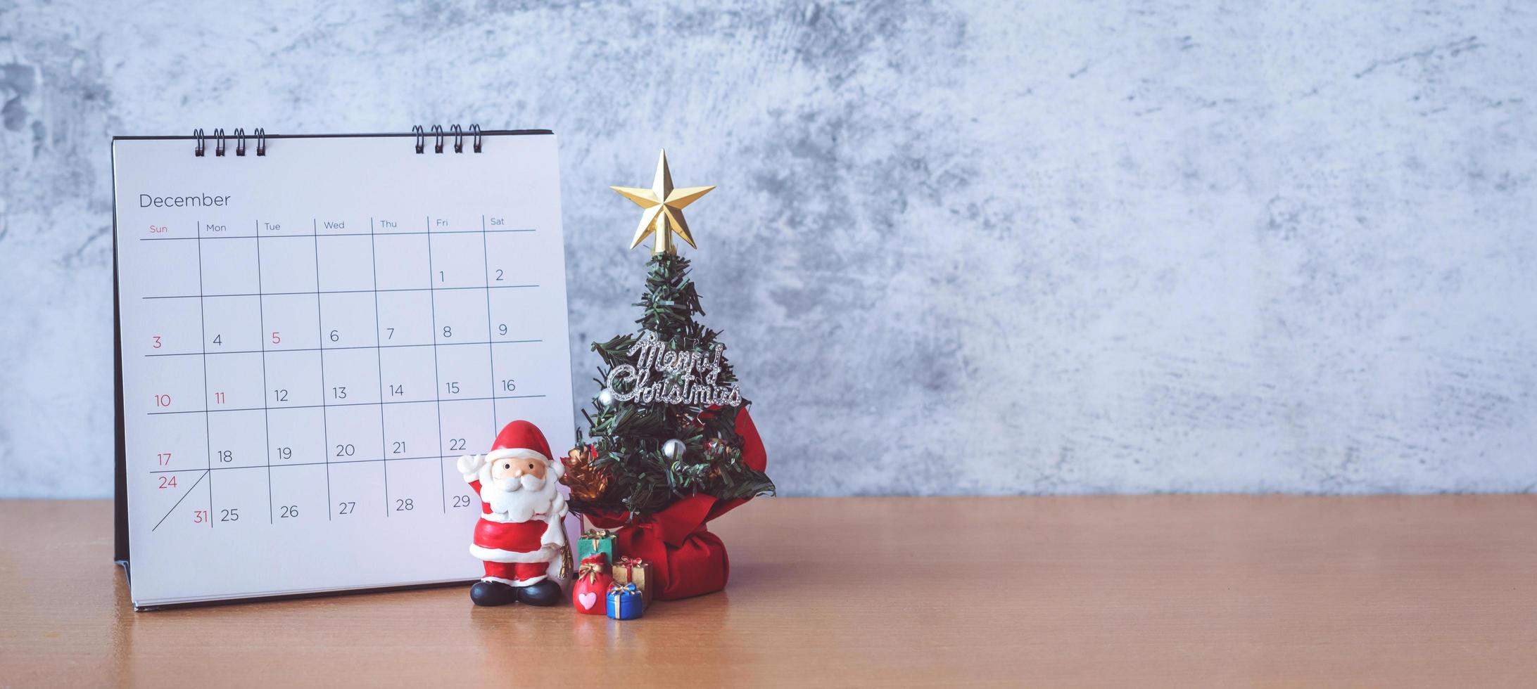 calendario di dicembre e decorazioni natalizie - Babbo Natale, albero e regalo su tavola di legno. concetto di natale e felice anno nuovo foto