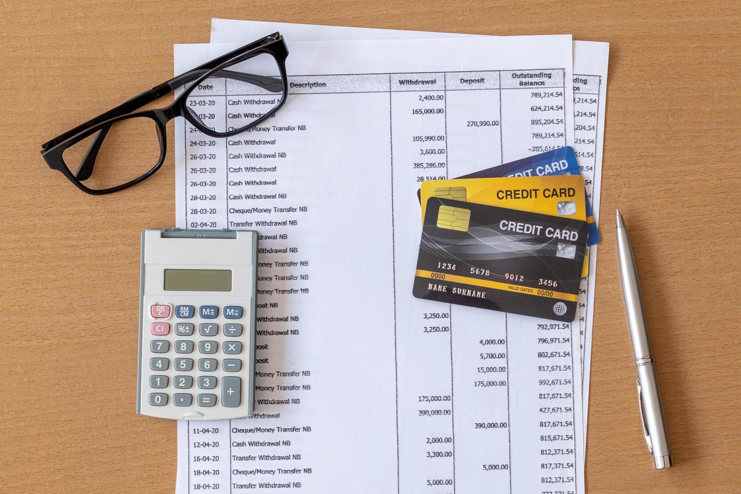 carte di credito e calcolatrice sull'estratto conto bancario su un tavolo di legno foto