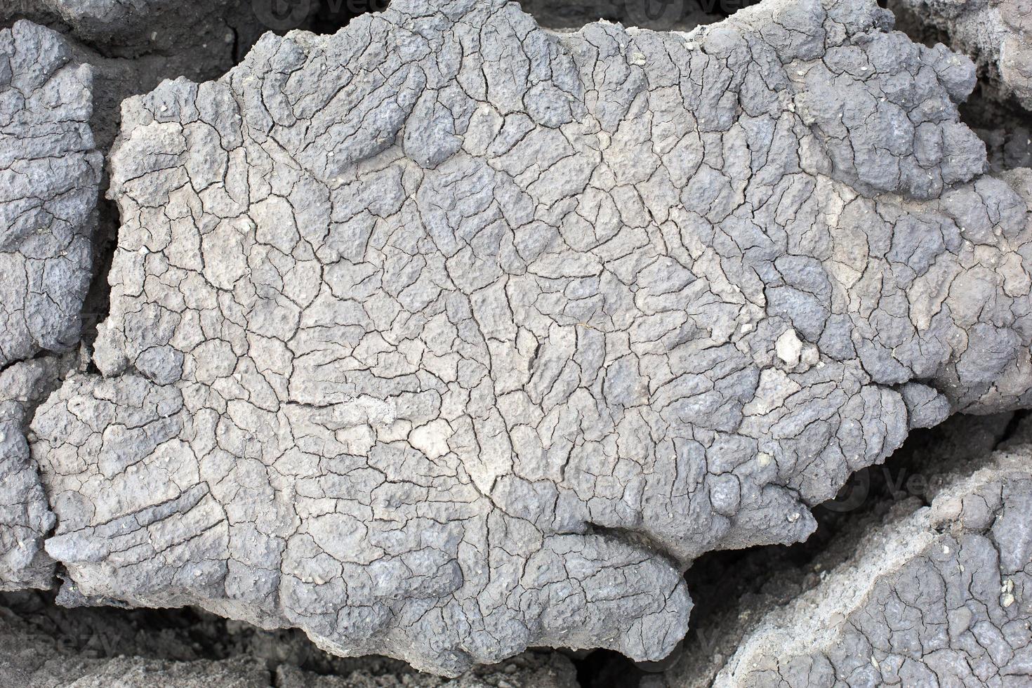 la consistenza della terra grigia screpolata, argilla vulcanica essiccata con crepe. grigio definitivo. sfondo naturale, copyspace foto