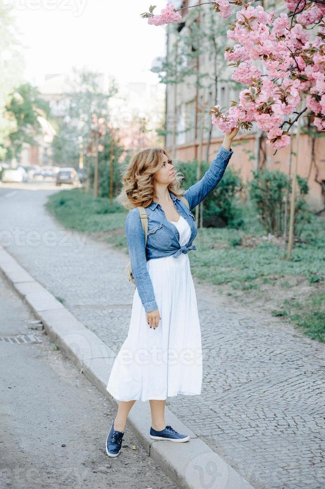 bella donna che si gode il campo delle margherite, bella donna sdraiata nel prato di fiori, bella ragazza che si rilassa all'aperto, divertendosi, tenendo la pianta, giovane donna felice e natura verde primaverile, concetto di armonia foto