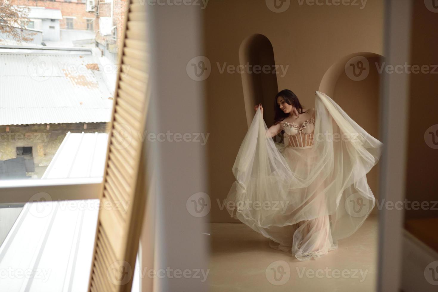 giovane ragazza in abito all'interno della stanza si siede nella finestra foto