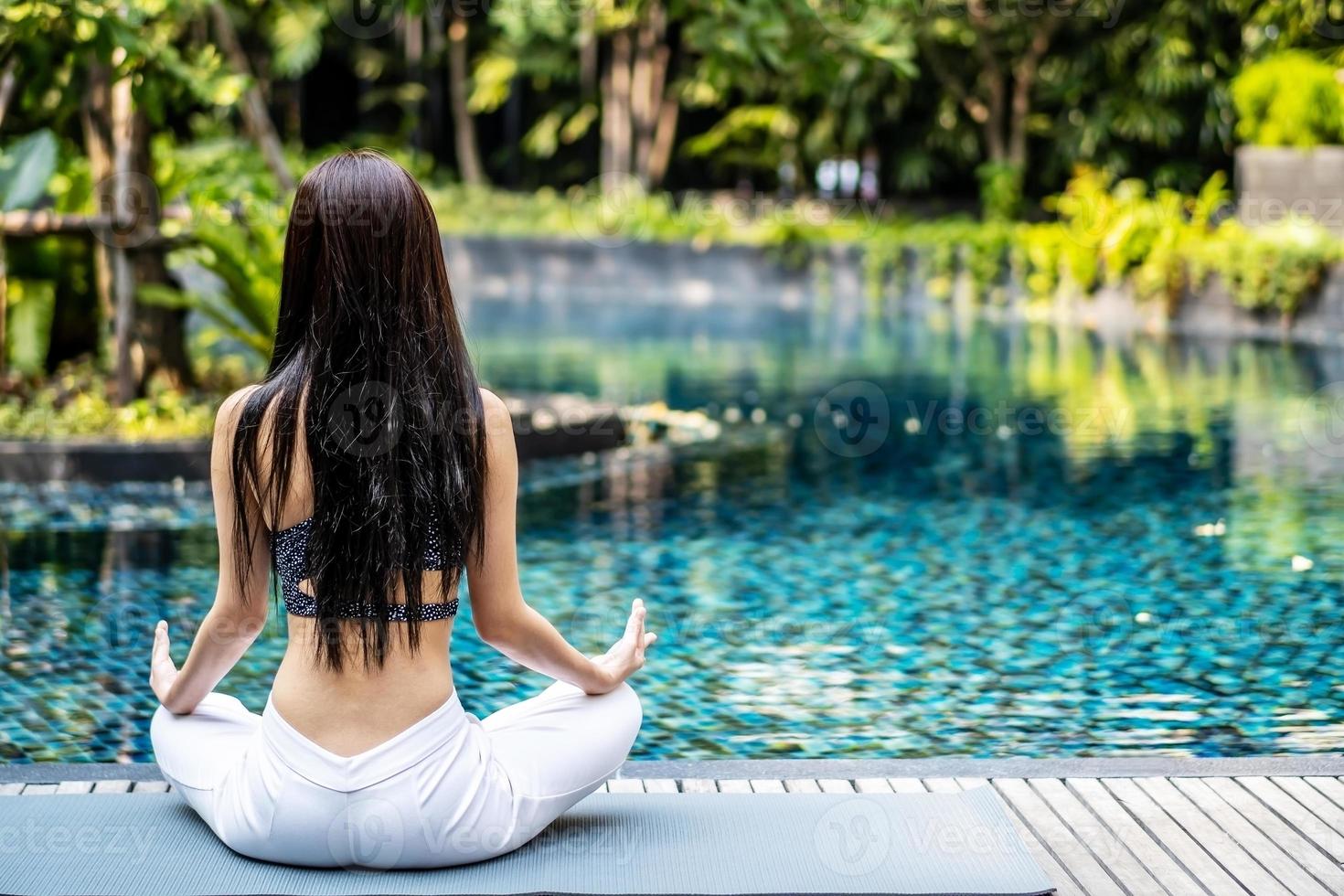 donna che allena yoga e meditazione in una posizione yoga di loto nella piscina blu foto
