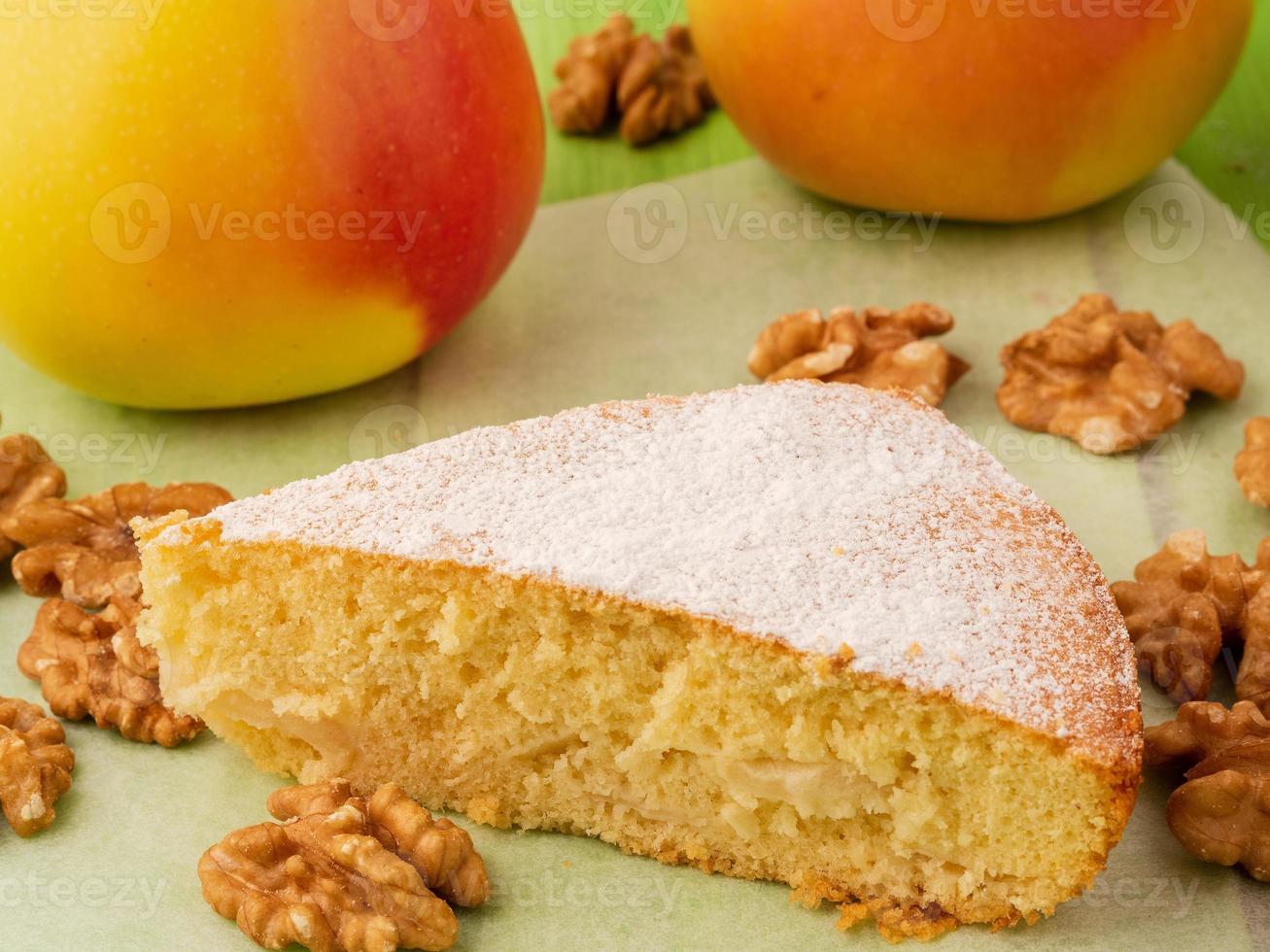 un pezzo di charlotte su pergamena, noci e mele. pasta biscotto torta di mele decorata con zucchero a velo foto