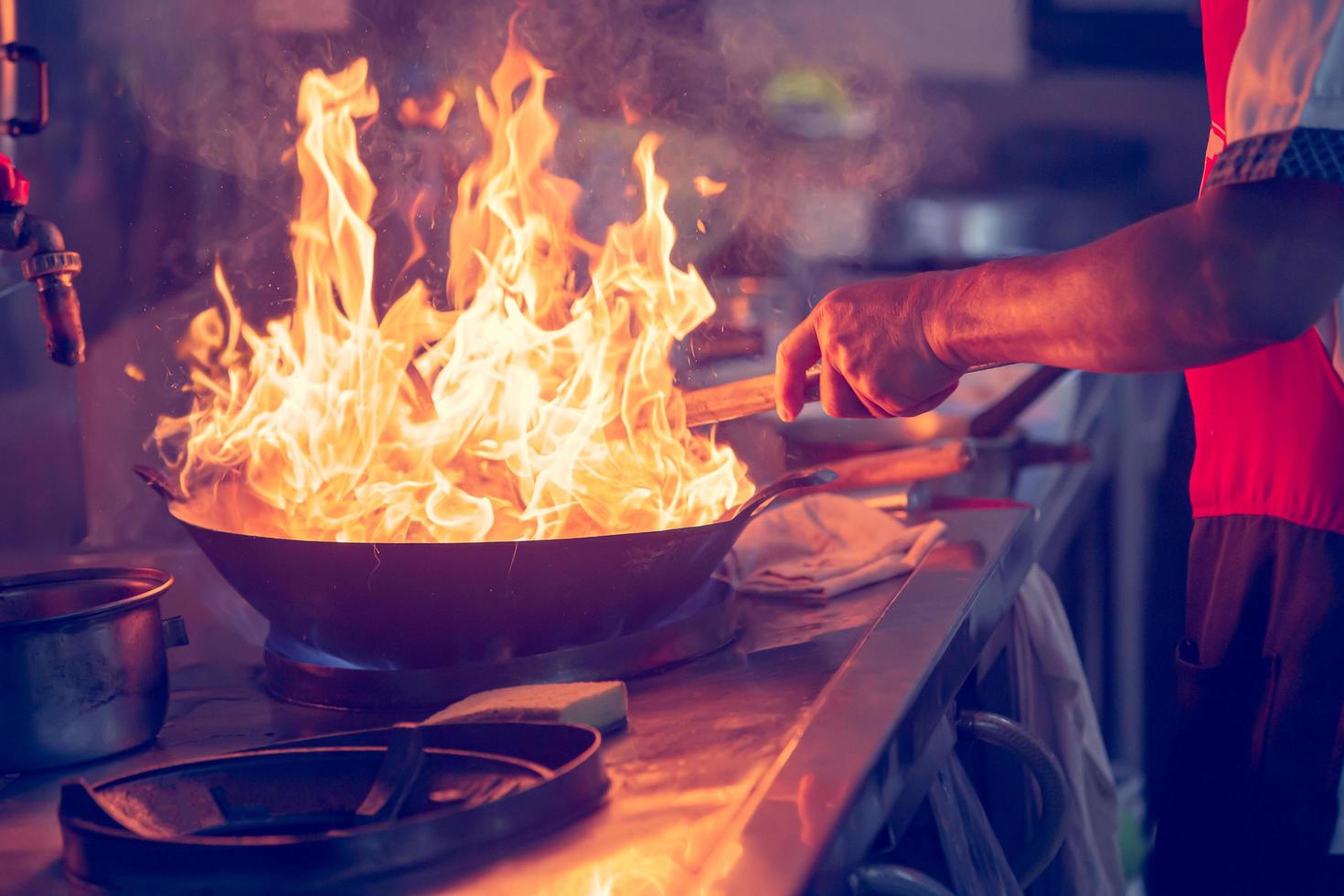 i movimenti dello chef durante la cottura in cucina con il fuoco in padella foto