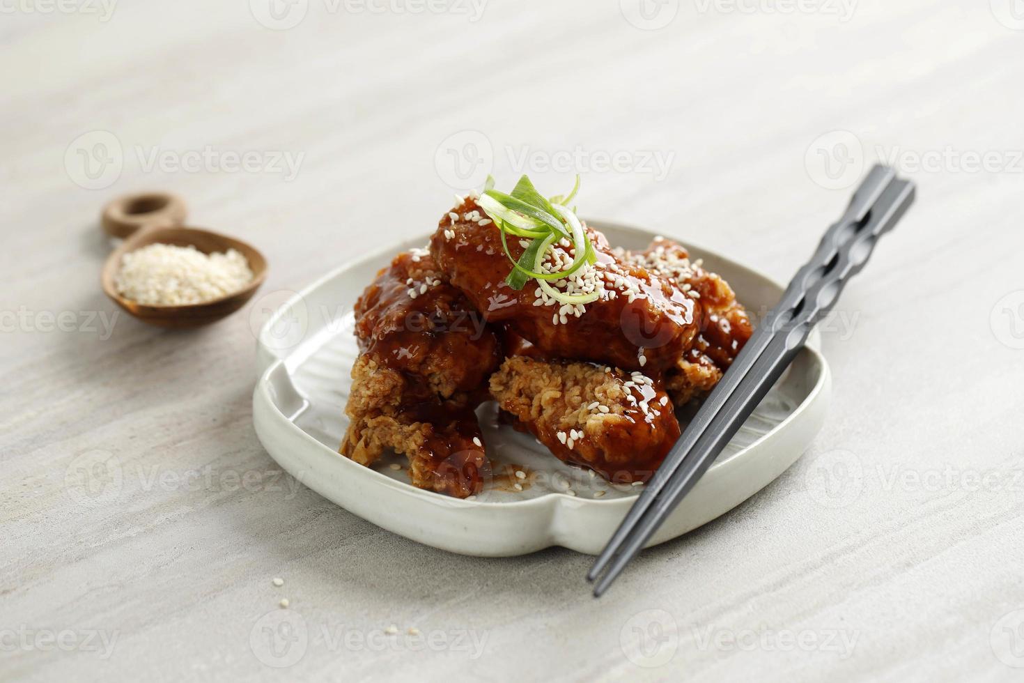 yangnyeom tongdak coreano piccante pollo fritto condita con sesamo bianco sul tavolo di cemento grigio foto