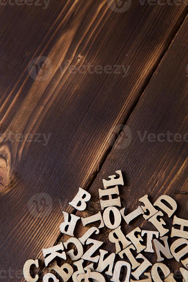 lettere dell'alfabeto inglese su uno sfondo di legno scuro. il concetto di educazione, giochi di parole, ricamo. spazio per il testo foto