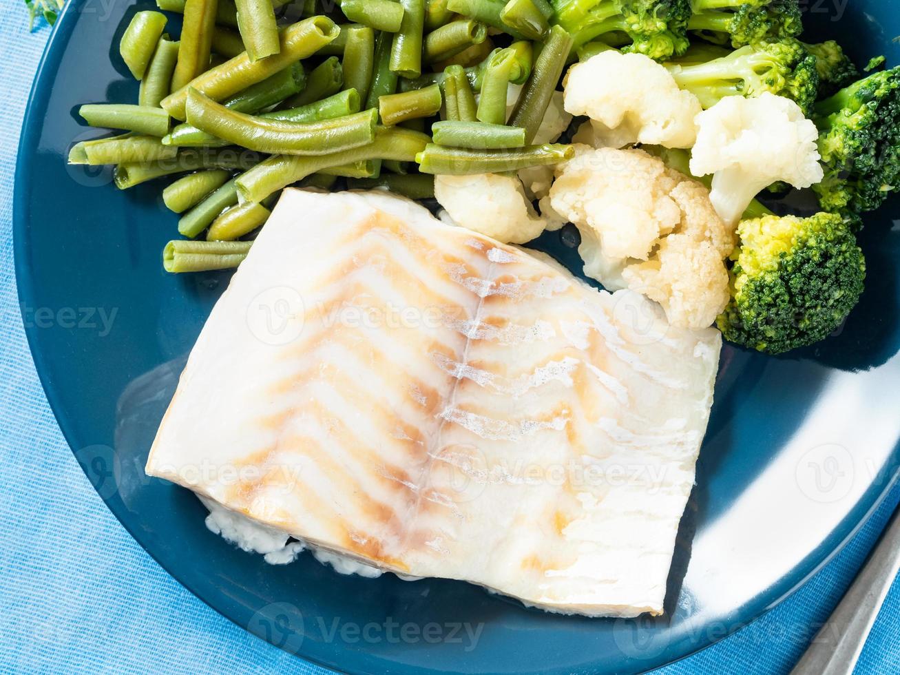 filetto di merluzzo ai frutti di mare al vapore con verdure su un piatto blu, vista dall'alto, primo piano. cibo dietetico sano per una corretta alimentazione foto