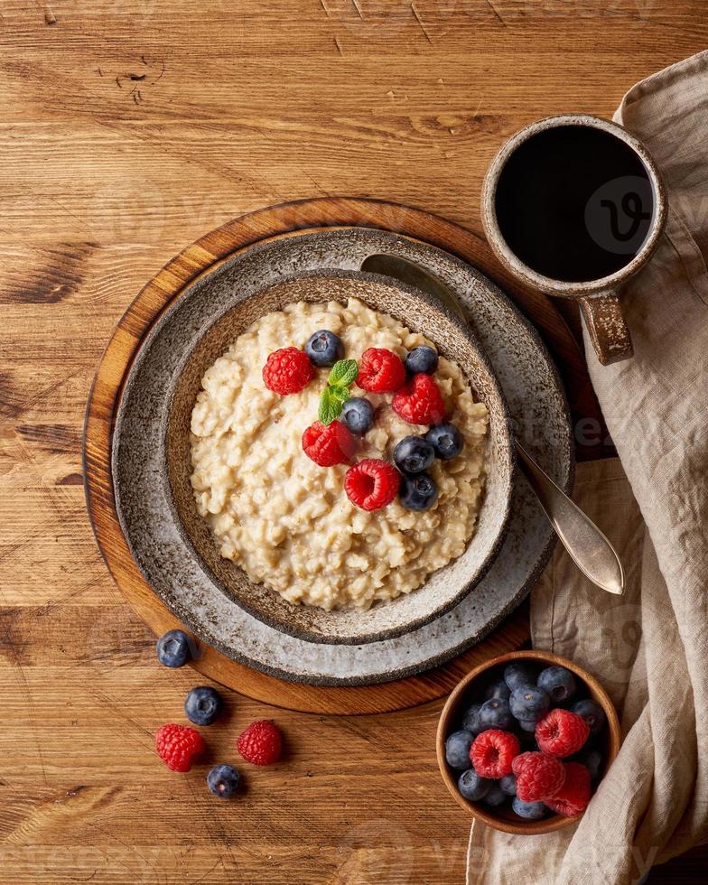 porridge rustico di farina d'avena con mirtillo, lamponi in ciotola vintage in ceramica, dieta dash con frutti di bosco foto