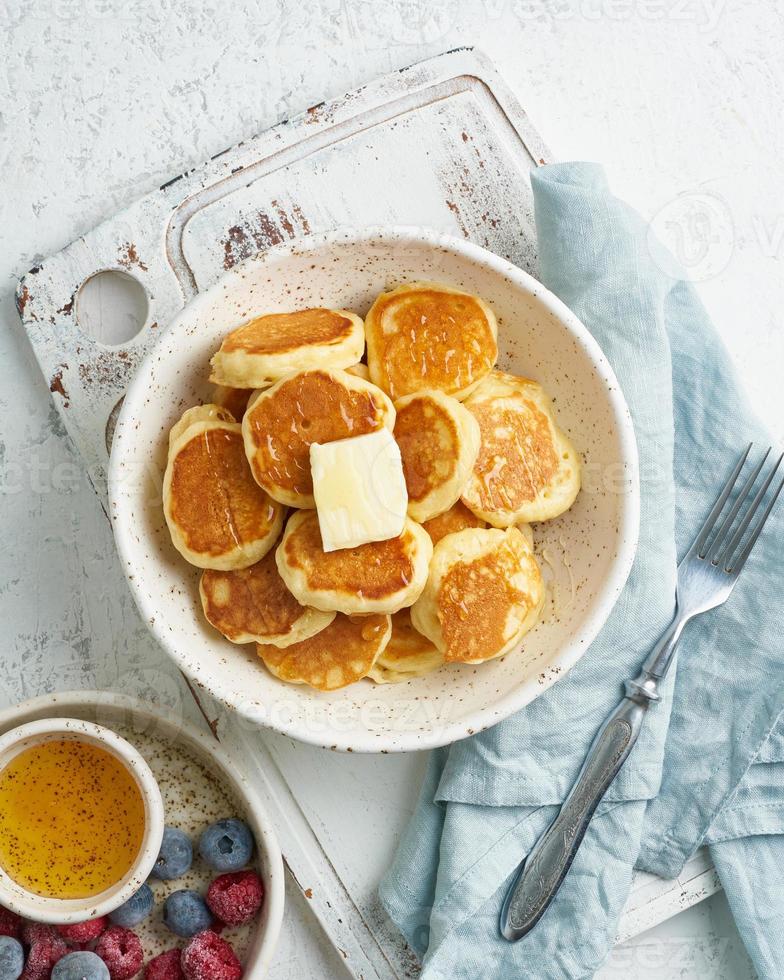 frittelle di cereali, piccola focaccina sottile e divertente, cibo per bambini. colazione con bevanda, tavolo bianco foto