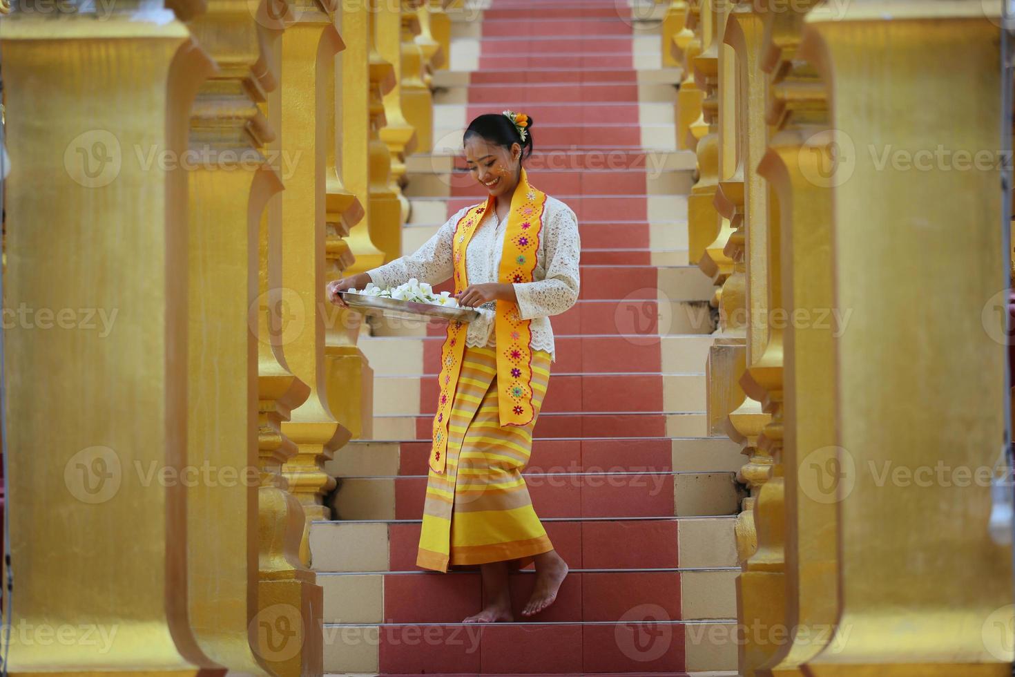 giovane ragazza asiatica in costume tradizionale birmano che tiene una ciotola di riso a portata di mano alla pagoda dorata nel tempio del myanmar. donne del Myanmar che tengono fiori con abiti tradizionali birmani che visitano un tempio buddista foto