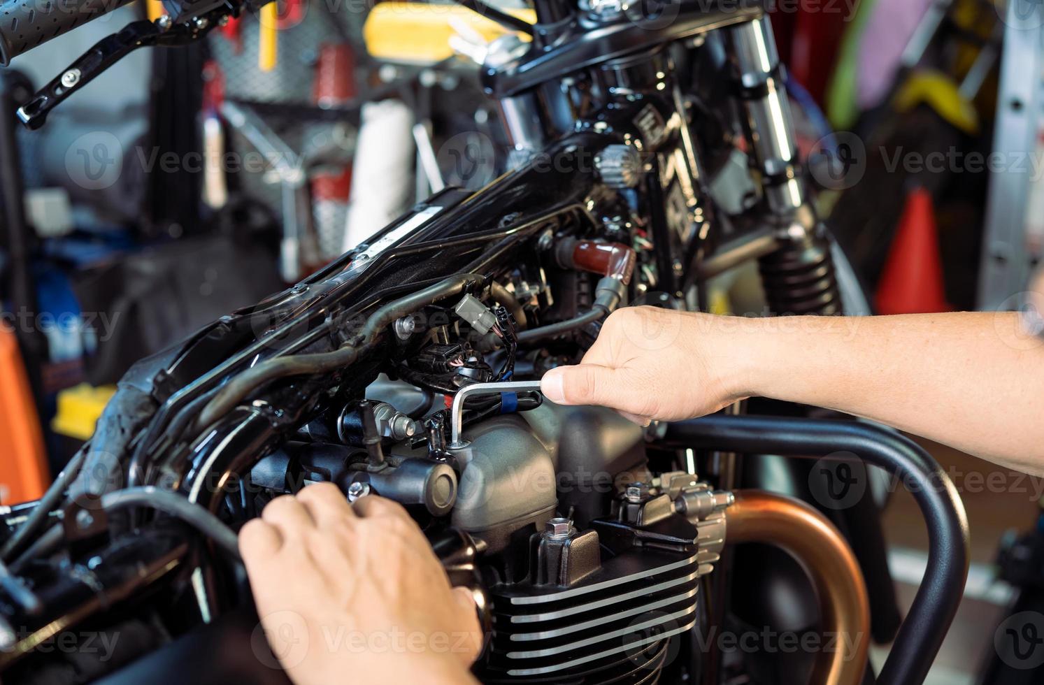 meccanico che utilizza una chiave inglese e una presa sulla motocicletta in garage .manutenzione, riparazione moto concetto .messa a fuoco selettiva foto