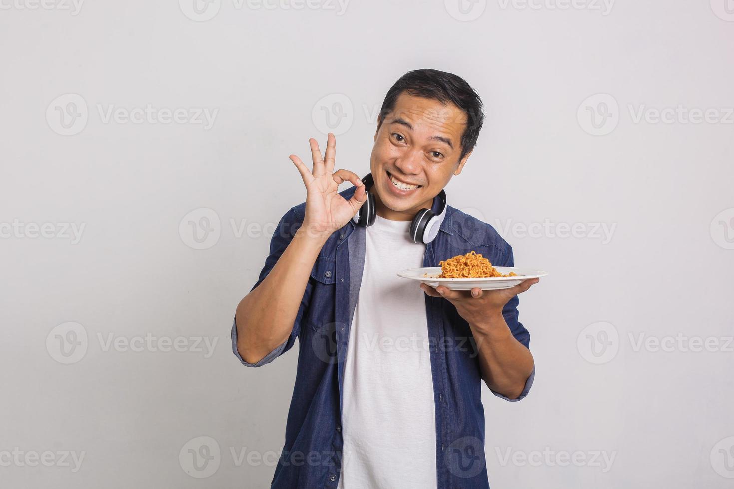 uomo asiatico che mangia spaghetti istantanei e si sente sorpreso da quanto sia delizioso foto