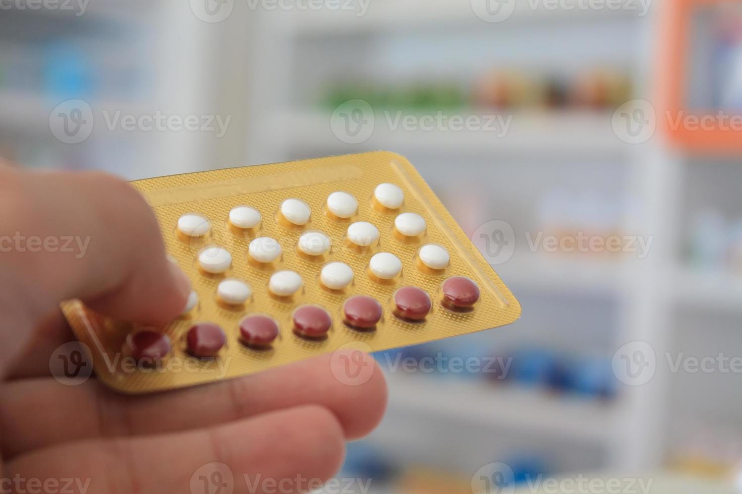 primo piano delle mani del farmacista che tengono le pillole contraccettive foto