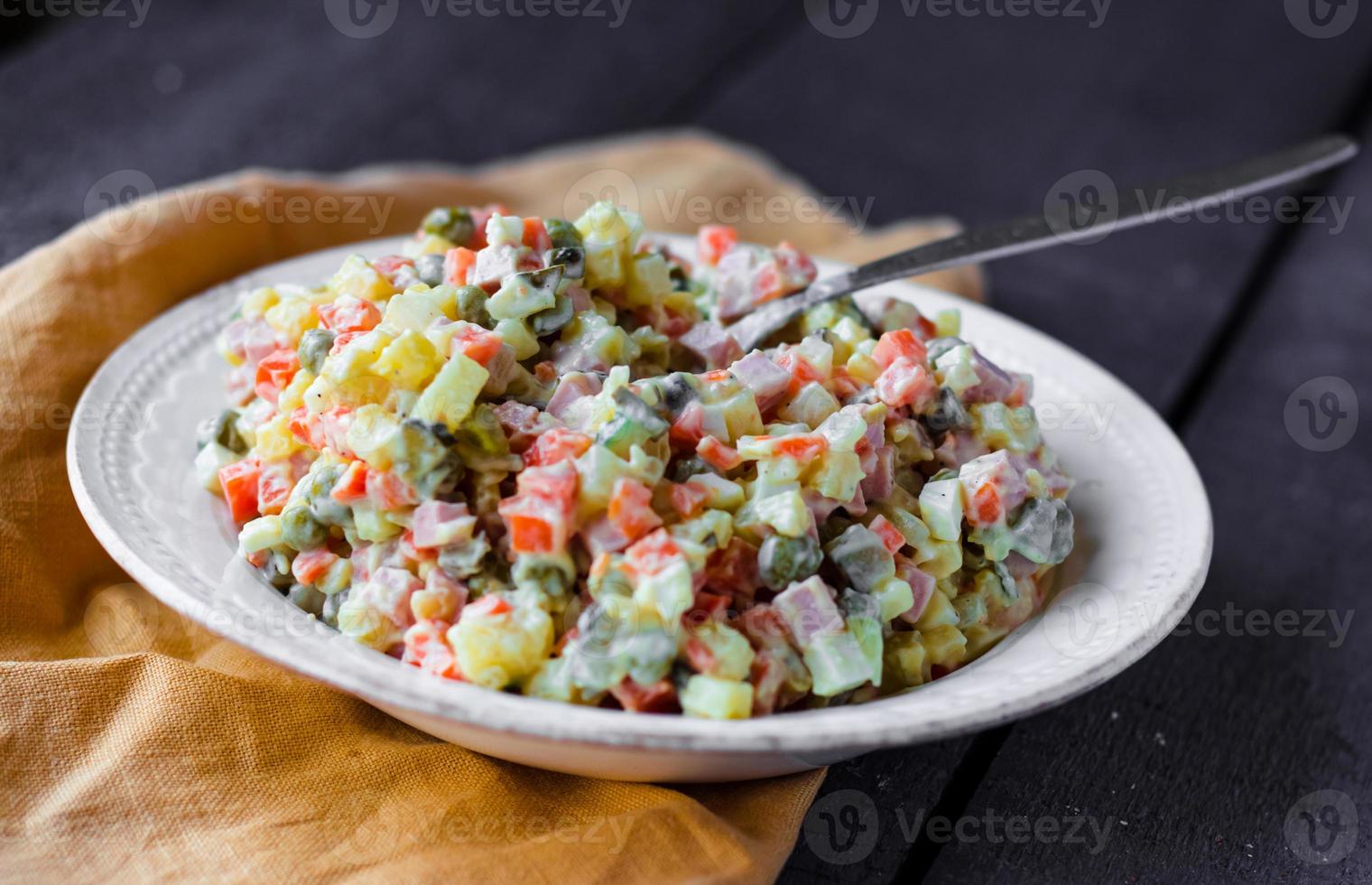insalata russa tradizionale più olivier con pisello nel piatto foto