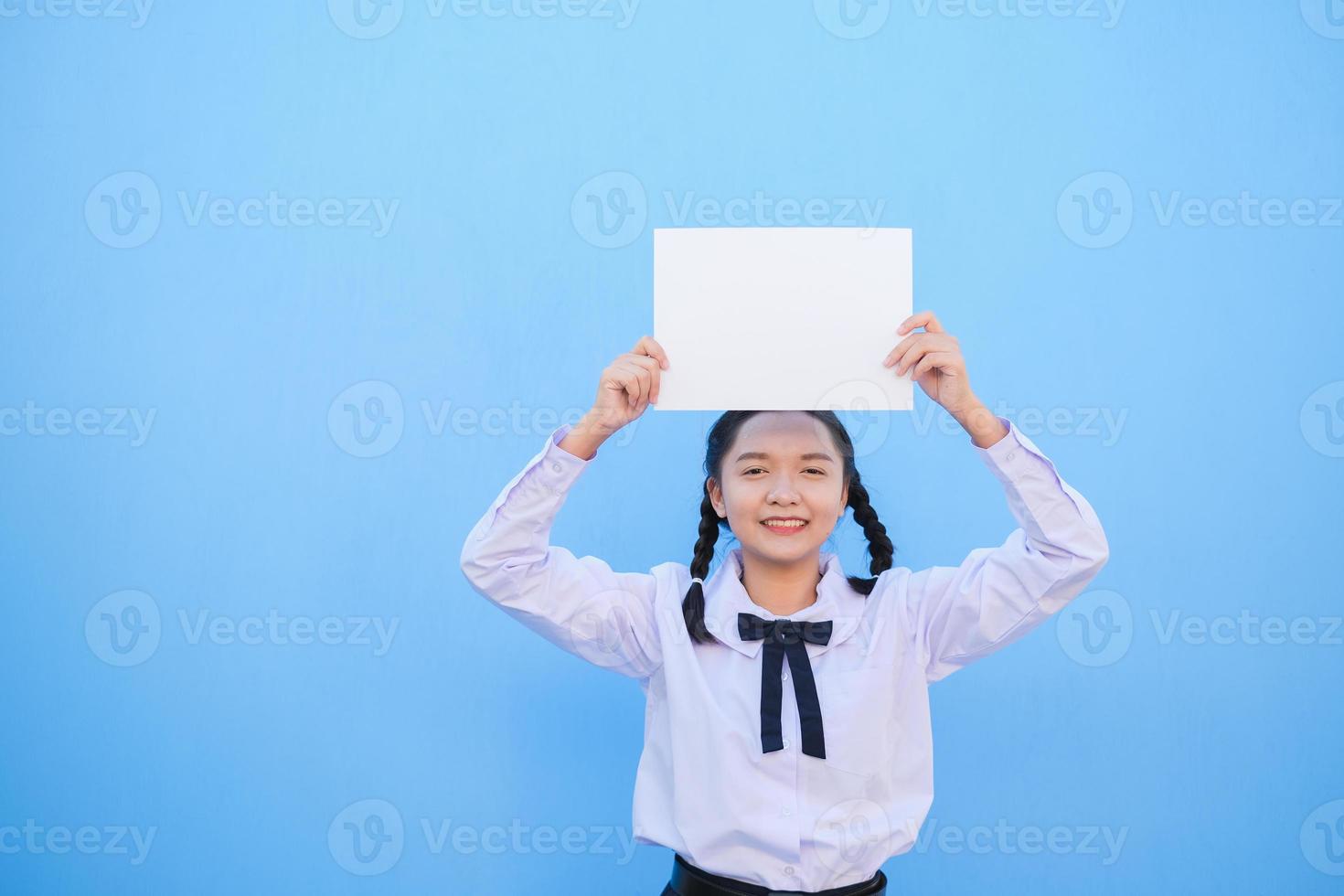 ragazza della scuola che tiene cartellone su sfondo blu. foto