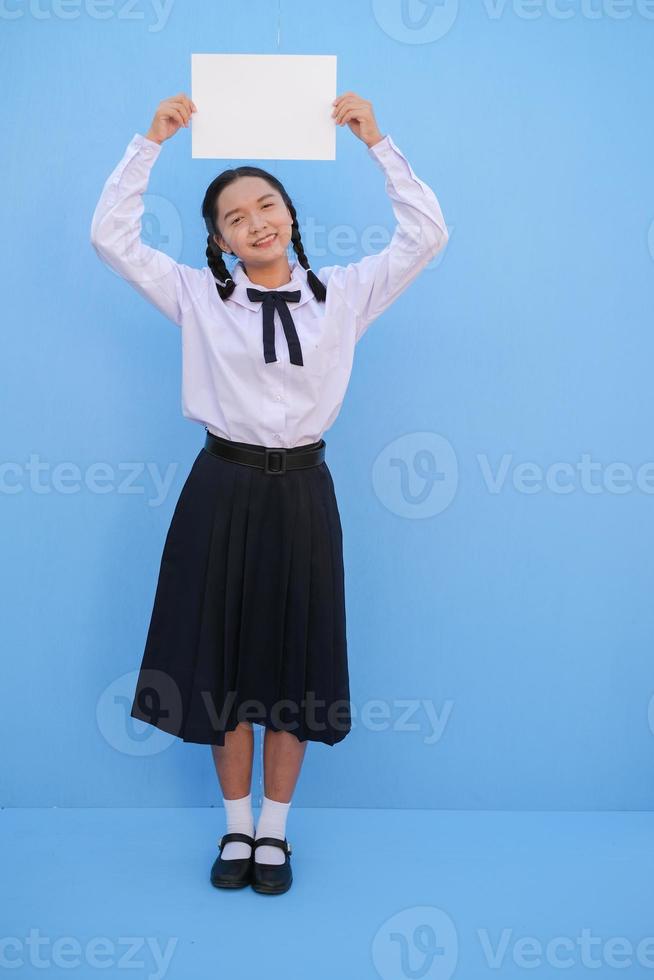 ragazza della scuola che tiene cartellone su sfondo blu. foto