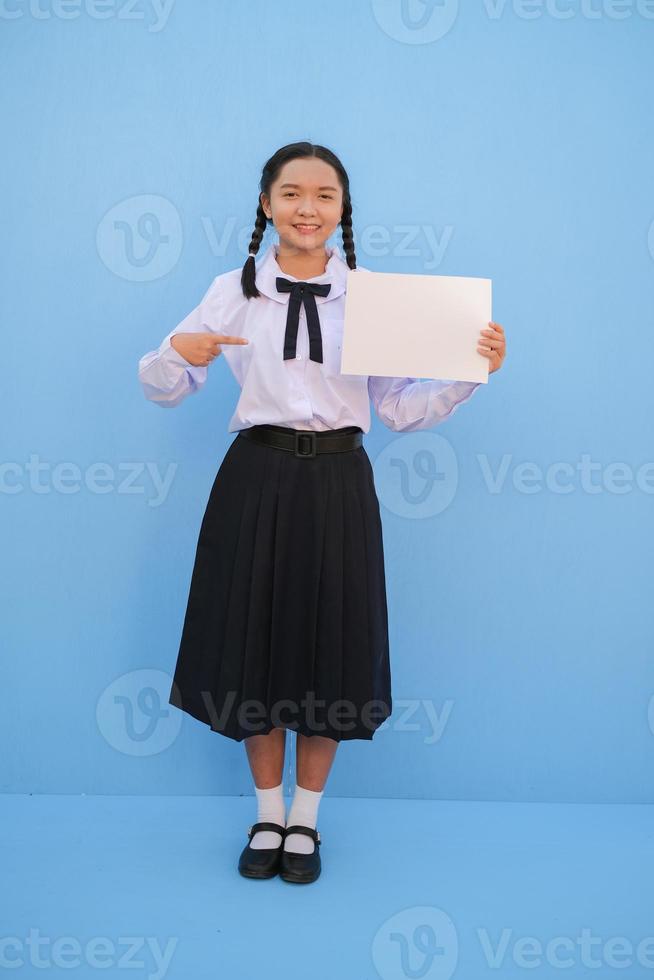 ragazza della scuola che tiene cartellone su sfondo blu. foto