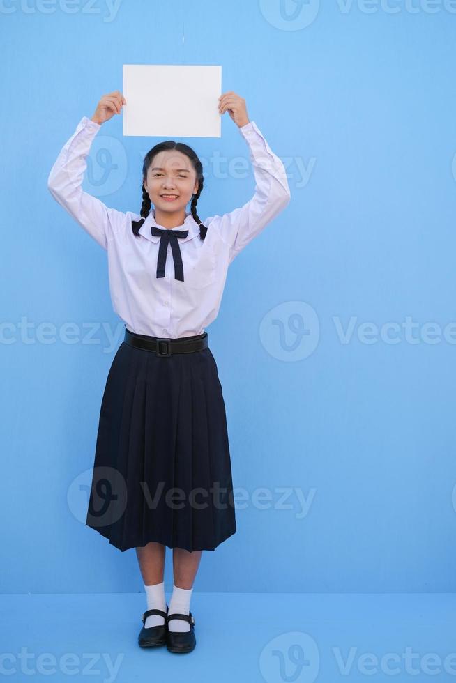 ragazza della scuola che tiene cartellone su sfondo blu. foto