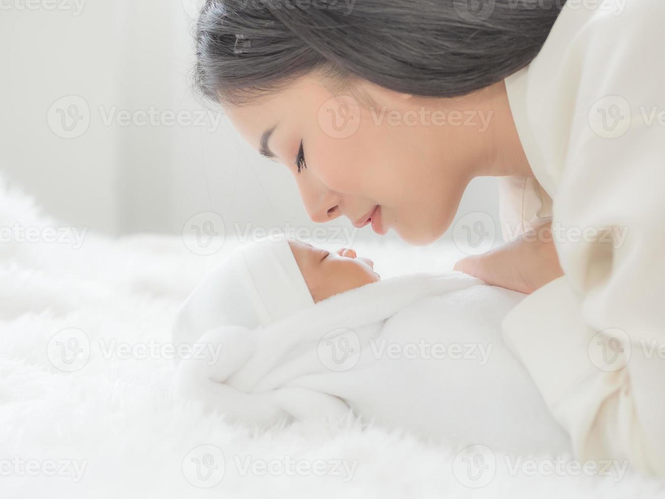 una bella donna asiatica sta guardando il suo neonato con felicità e amore foto